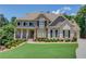 Beautiful two-story home featuring a stone and brick facade, manicured lawn, and covered front porch at 255 Beech Tree Holw, Sugar Hill, GA 30518