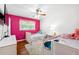 Bright bedroom with two beds, hardwood floors, a ceiling fan, a window, and a vibrant pink accent wall at 3248 Wildwood Sw Dr, Marietta, GA 30060