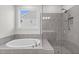 Luxurious bathroom showcasing a soaking tub and a separate shower with gray tiles and modern fixtures at 4011 Fallen Leaf Ct, Kennesaw, GA 30152