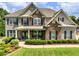 Charming home featuring brick and stone facade, lush landscaping, and a welcoming front porch at 5220 Southern Hills Ln, Cumming, GA 30040