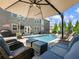 Backyard pool with cozy seating under a large umbrella and the American flag hanging on the back of the house at 5220 Southern Hills Ln, Cumming, GA 30040