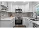 Bright kitchen with white cabinets, stainless steel appliances, tile backsplash, and modern fixtures at 6090 Heritage Se Way, Mableton, GA 30126