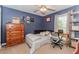 Bedroom with a blue accent wall, hardwood furnishings, and natural light from the window at 1205 Rivershyre Ne Pkwy, Lawrenceville, GA 30043