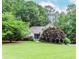 Landscaped home exterior boasting a well-manicured lawn, mature trees, and a charming front entrance at 1205 Rivershyre Ne Pkwy, Lawrenceville, GA 30043
