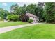 Traditional home with a lush green lawn, mature trees, and a long driveway leading to the two-car garage at 1205 Rivershyre Ne Pkwy, Lawrenceville, GA 30043
