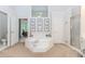 Bright bathroom with a large tub, a walk-in shower with gold trim, and a vanity with an accent mirror at 1205 Rivershyre Ne Pkwy, Lawrenceville, GA 30043