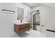 Modern bathroom with marble tiled walls, floating vanity, a mirror, and open doorway to a bedroom with natural light at 1887 Shalimar Dr, Atlanta, GA 30345
