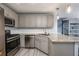 Kitchen with stainless steel appliances, granite countertops, grey cabinets, and a spiral staircase at 2507 Albion Farm Way, Duluth, GA 30097