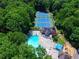 Aerial view of blue tennis courts, pool, clubhouse and playground, all surrounded by lush trees at 2628 Amberly Dr, Dunwoody, GA 30360