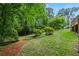 Beautifully landscaped backyard with a mix of trees, shrubs, and green grass at 3802 Sw Knights Bridge Sw Rd, Lilburn, GA 30047