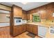 Charming kitchen featuring wood cabinets, white appliances, and a window over the sink at 3802 Sw Knights Bridge Sw Rd, Lilburn, GA 30047