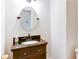 Elegant half bathroom featuring an oval mirror, black countertop, and dark wood cabinets at 251 Waterford Cove Dr, Suwanee, GA 30024