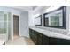 Well-lit bathroom with double vanities and large mirrors, with a glass shower door and tile flooring at 251 Waterford Cove Dr, Suwanee, GA 30024