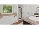 A stunning primary bathroom features a soaking tub, walk-in shower, and wood-look tile flooring at 5414 Sycamore Rd, Oakwood, GA 30518