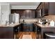 Well-lit kitchen features dark wood cabinets, stainless steel appliances, and granite countertops at 5414 Sycamore Rd, Oakwood, GA 30518