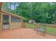 Large wooden deck with a black metal chair, railing, and a view of the backyard and a screened-in porch at 2149 New London Place Pl, Snellville, GA 30078