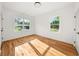 Sun-filled bedroom with hardwood floors, white walls, and two windows at 327 Ohm Ave, Avondale Estates, GA 30002
