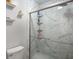 Close up of a bathroom shower featuring marble-like tile walls with glass doors and shelving inside at 2795 Bentwood Dr, Marietta, GA 30062