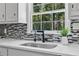 Kitchen sink features black faucet, mosaic backsplash, granite countertop and window with view at 5706 Brookstone Nw Walk, Acworth, GA 30101
