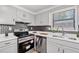 A modern kitchen featuring stainless steel appliances, gray cabinets, and stylish backsplash at 4771 N Springs Nw Rd, Kennesaw, GA 30144