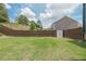 Lush green backyard featuring a privacy fence and a storage shed at 5789 Creek Indian Dr, Sugar Hill, GA 30518