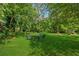 Expansive backyard with manicured lawn, patio table set, and a fire pit, surrounded by trees at 13795 Arnold Mill Rd, Roswell, GA 30075