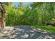 Backyard stone patio area surrounded by lush greenery and mature trees at 13795 Arnold Mill Rd, Roswell, GA 30075