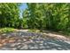 Gravel driveway with ample parking space surrounded by lush greenery and mature trees at 13795 Arnold Mill Rd, Roswell, GA 30075