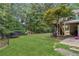 A spacious backyard with lush grass, surrounded by mature trees, and featuring play equipment for outdoor fun and relaxation at 25 Grange Ct, Sharpsburg, GA 30277