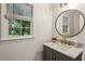 Stylish half-bath featuring a modern vanity, gold fixtures, and a round mirror at 3145 Indian Hills Ne Dr, Marietta, GA 30068