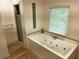 Bathroom featuring large tub with jets, glass block window, and a shower with glass door at 4590 River Stone Trl, Douglasville, GA 30135