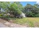 Quaint white home with a welcoming front porch, surrounded by mature trees and a green lawn at 1052 Curran Nw St, Atlanta, GA 30318