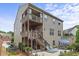 Back of home featuring a wooden staircase, two balconies, and a stone patio with an outdoor dining area and lounge chairs at 1850 Overlook Springs Ln, Cumming, GA 30040