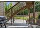 Outdoor patio area under wooden staircase featuring a grill, wicker chairs and view of fenced backyard at 1850 Overlook Springs Ln, Cumming, GA 30040