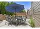 Backyard patio with an outdoor dining set, an umbrella, and a view of the landscaped backyard with wooden staircase at 1850 Overlook Springs Ln, Cumming, GA 30040