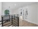 Bright hallway with modern railing, hardwood floors, and adjacent laundry room at 2631 Sardis Way, Buford, GA 30519