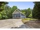 View of blue home from cracked driveway with fenced backyard area and treeline at 735 Poplar Rd, Dallas, GA 30157