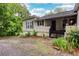 Exterior view of the home, featuring black shutters, front porch, and partial yard with green space and plants at 791 E Main Street, Canton, GA 30114