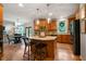 Bright kitchen features wood cabinets, hardwood floors, island with pendant lights, and black stainless refrigerator at 685 Sienna Dr, Cumming, GA 30040