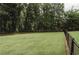 A large, well-maintained lawn stretches out towards a backdrop of mature trees and chain link fence at 8394 Banks Mill Rd, Douglasville, GA 30135