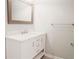 Bathroom vanity featuring marble countertop, white cabinets with chrome pulls, and a framed mirror at 8394 Banks Mill Rd, Douglasville, GA 30135