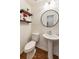 Cozy powder room with pedestal sink, round mirror, wood floors, and floating shelves at 429 Deckner Sw Ave, Atlanta, GA 30310