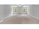 A large bedroom with neutral colored carpet, walls, and trim, plus two bright and sunny windows at 350 Paces Dr, Lithia Springs, GA 30122