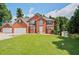 A beautiful two-story brick home with a well-manicured lawn and three car garage on a sunny day at 3524 Forest Downs Cv, Decatur, GA 30034