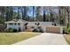 Charming white brick home featuring a long driveway, attached garage and manicured front yard and wooded backdrop at 1978 Fisher Ne Trl, Atlanta, GA 30345