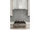 Close-up of a stainless steel gas cooktop with grey backsplash and white cabinets at 2325 Mason Dr # D22, Atlanta, GA 30316