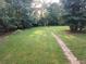 Expansive backyard surrounded by lush greenery featuring a playset and stone path at 3140 Kipling Dr, Powder Springs, GA 30127