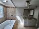 Bathroom featuring a double vanity, granite countertop, jacuzzi tub with a tile surround, and natural lighting at 3140 Kipling Dr, Powder Springs, GA 30127