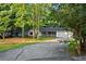 View of the home with mature trees, featuring red shutters, brick accents, white railing, and long driveway at 11006 Clearwater Dr, Hampton, GA 30228