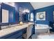 Bathroom featuring double sinks, marble counters, deep blue walls, soaking tub, and white tile floors at 1208 Brandl Sw Dr, Marietta, GA 30008